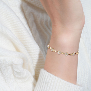 Goudkleurige armband met vijf moissanite bloemen en elegante draai-elementen – stijlvol en verfijnd.