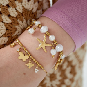 Goudkleurige armband met witte parels en hangers van een zeester, schelp en zeepaardje.